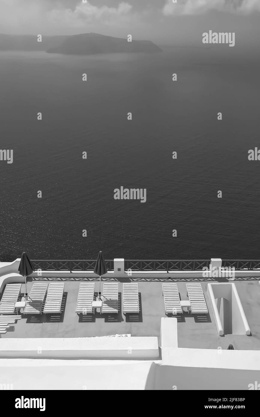 Une belle terrasse blanchie à la chaux avec chaises longues et une vue à couper le souffle sur la mer Égée à Santorini Grèce en noir et blanc Banque D'Images