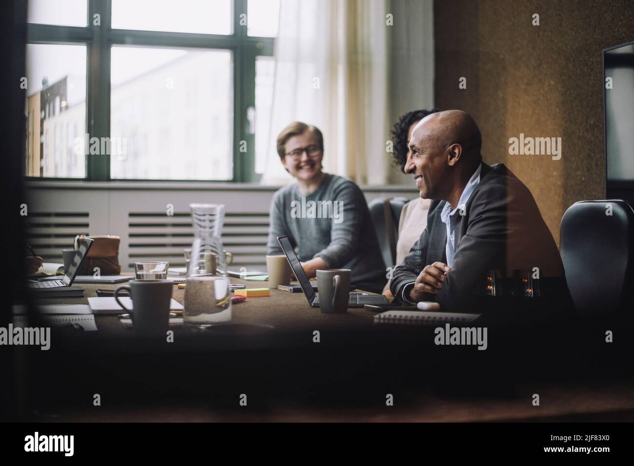 Heureux homme d'affaires mature assis par des collègues à la table de conférence au bureau Banque D'Images