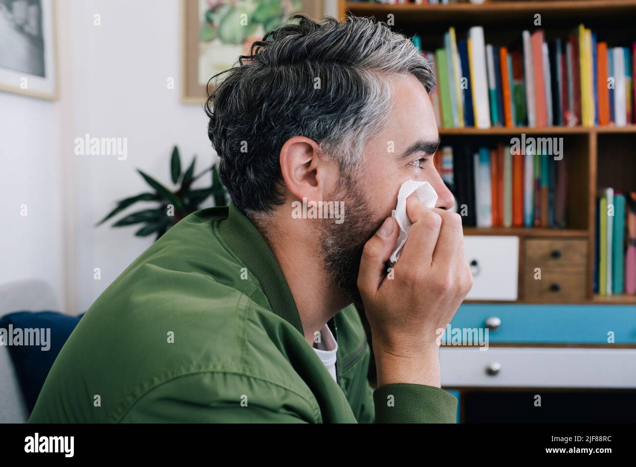Homme déprimé frottant le visage avec du papier de soie au bureau de thérapie Banque D'Images