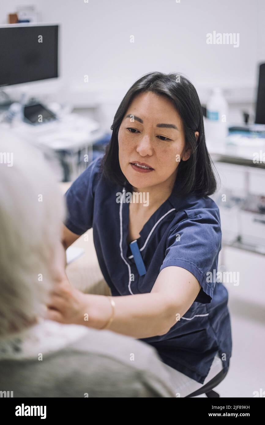 Une otolaryngologiste féminine examine la gorge d'un patient âgé en clinique médicale Banque D'Images