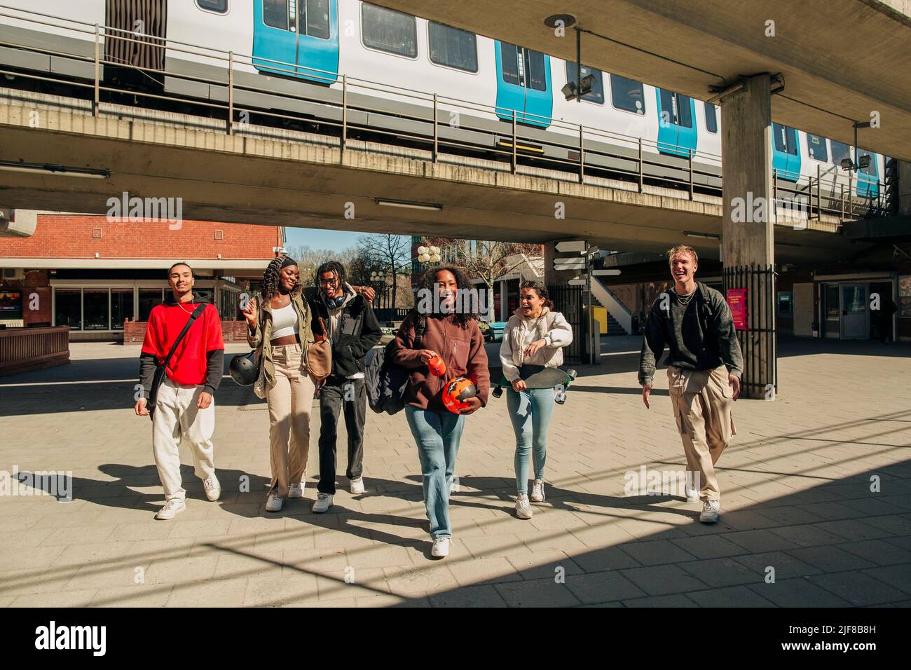 De jeunes amis multiraciaux heureux marchant ensemble dans la rue sous le pont Banque D'Images