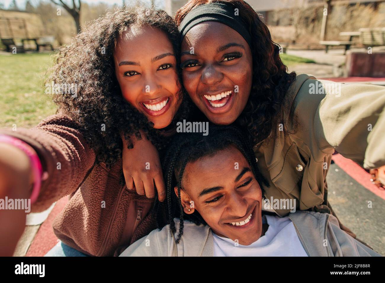 Portrait de jeunes femmes heureux prenant le selfie avec un ami masculin le jour ensoleillé Banque D'Images