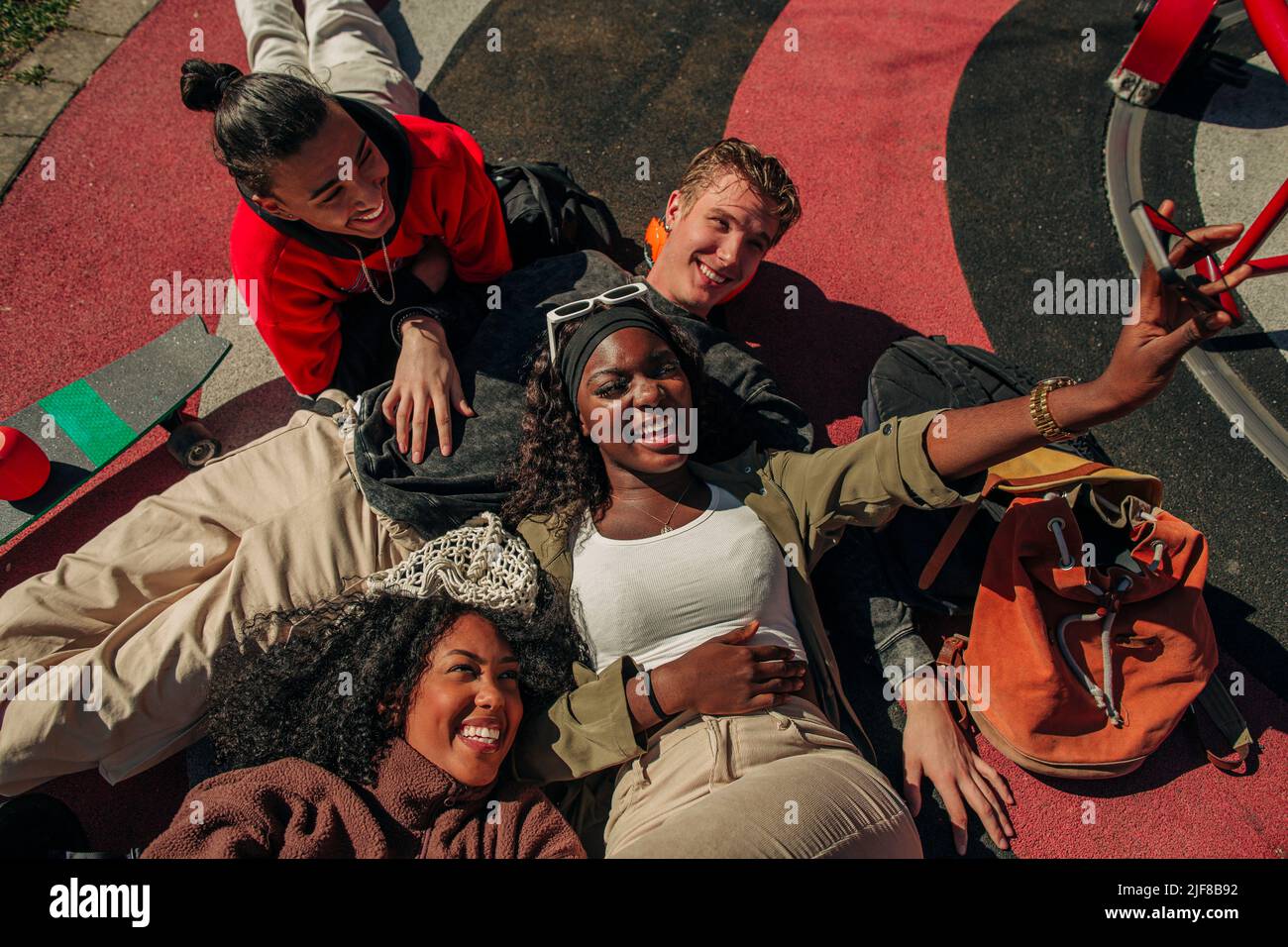 Vue en grand angle des amis multiraciaux gais qui prennent le selfie à travers le smartphone dans le terrain de jeu Banque D'Images