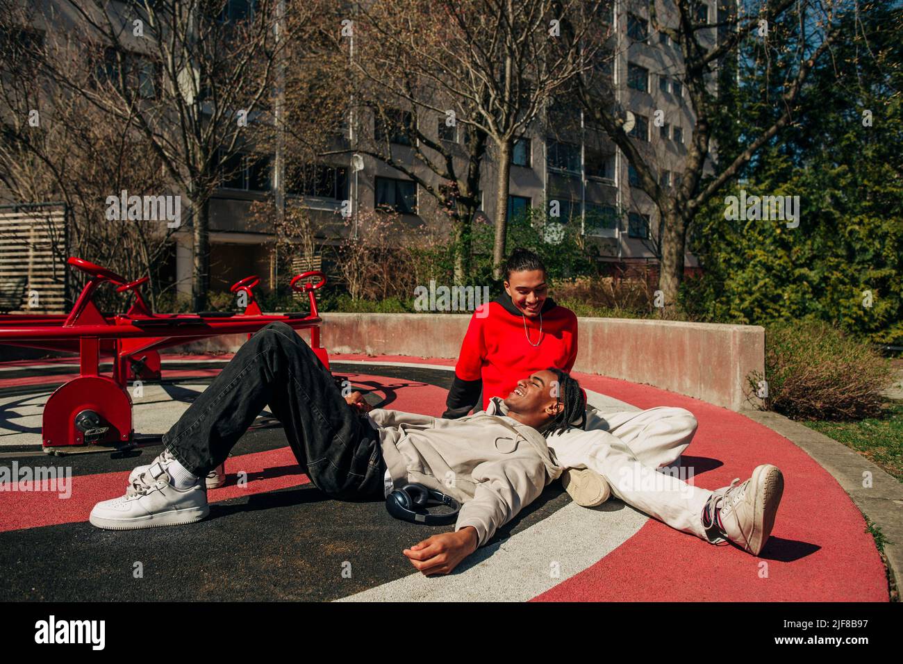 Des jeunes hommes souriants passent du temps libre dans l'aire de jeux par beau temps Banque D'Images