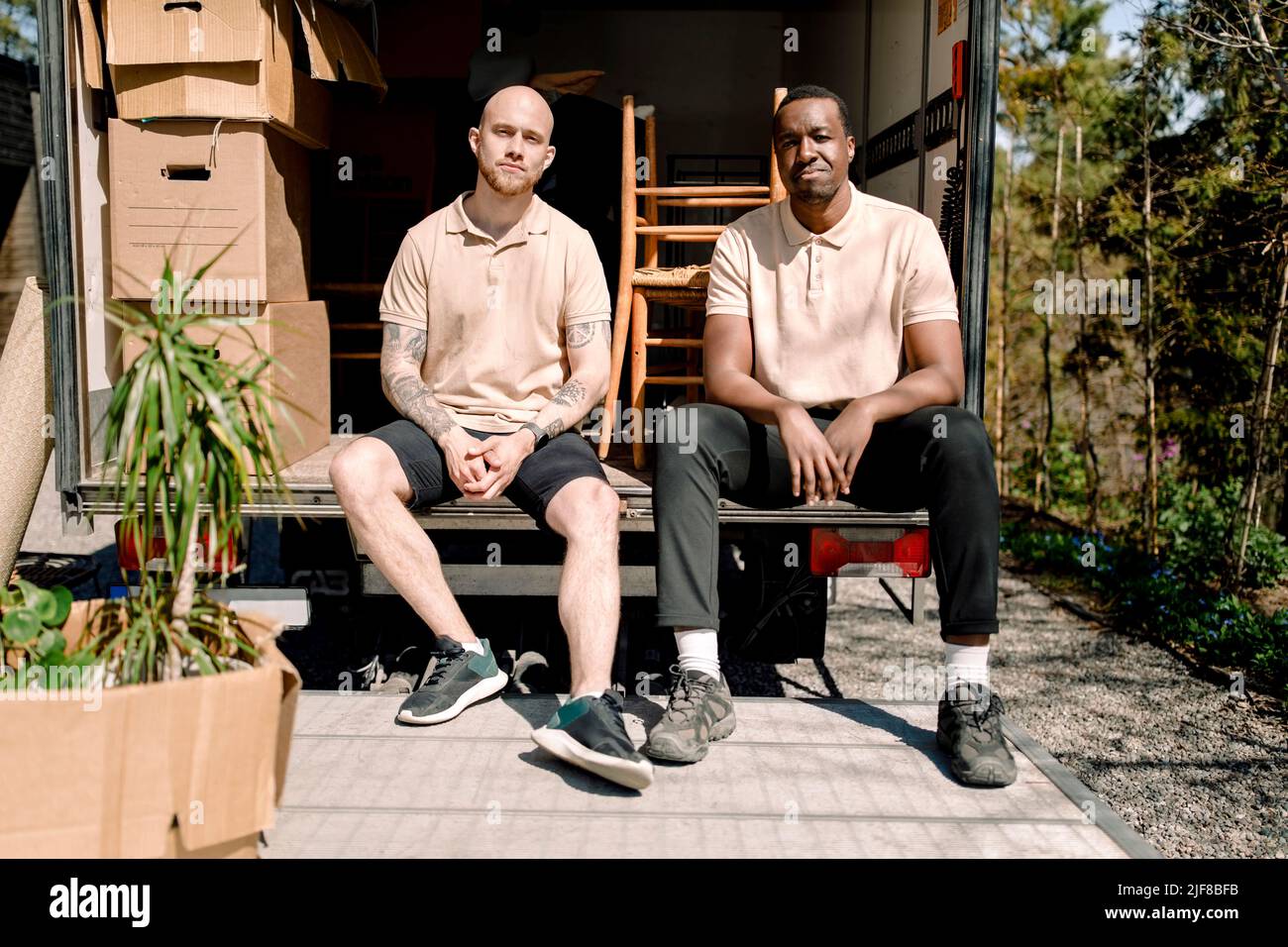 Portrait de movers multiraciaux assis dans le coffre du camion de livraison Banque D'Images