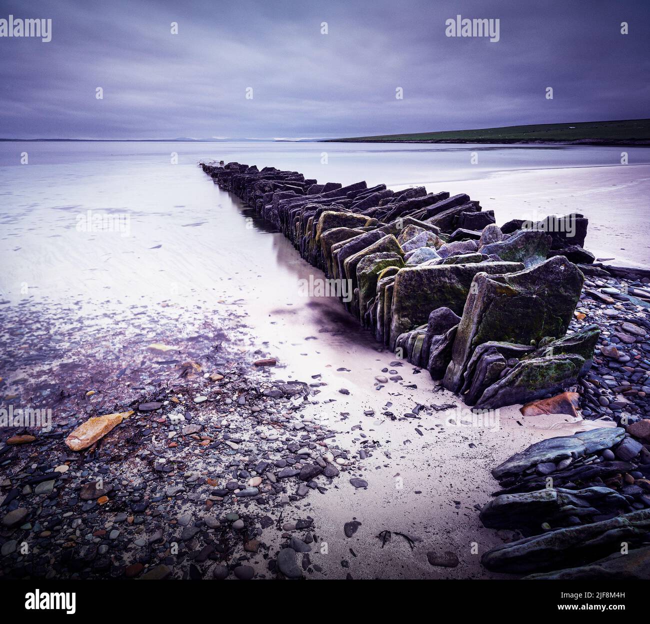 Ancienne structure en pierre s'étendant dans la mer depuis une plage d'Eday, Orkney Islands Banque D'Images