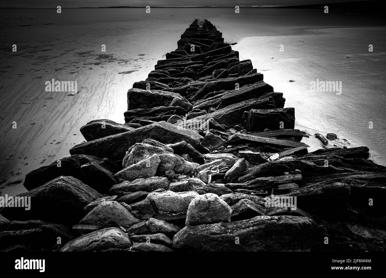 Ancienne structure en pierre s'étendant dans la mer depuis une plage d'Eday, Orkney Islands Banque D'Images