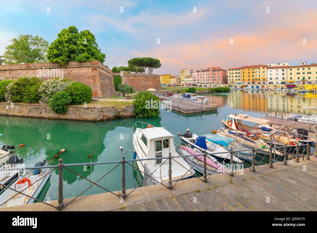Des bateaux bordent les canaux bondés à côté de la nouvelle forteresse et un café extérieur en bord de mer dans la ville toscane de Livourne, en Italie. Banque D'Images