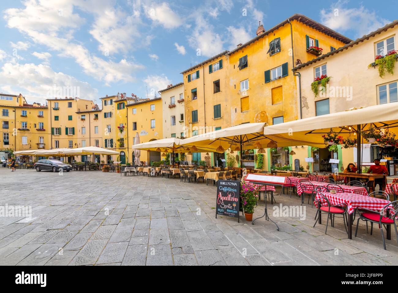 Cafés-terrasses à l'intérieur de la Piazza del Anfiteatro, l'ancien amphithéâtre de la ville toscane fortifiée de Lucques, en Italie. Banque D'Images