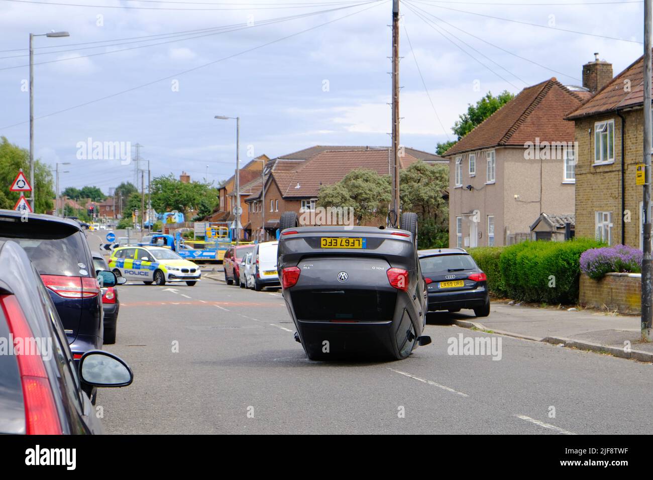 Une voiture renversée au milieu de la route, après avoir été suivie par la police, attend son enlèvement. Banque D'Images