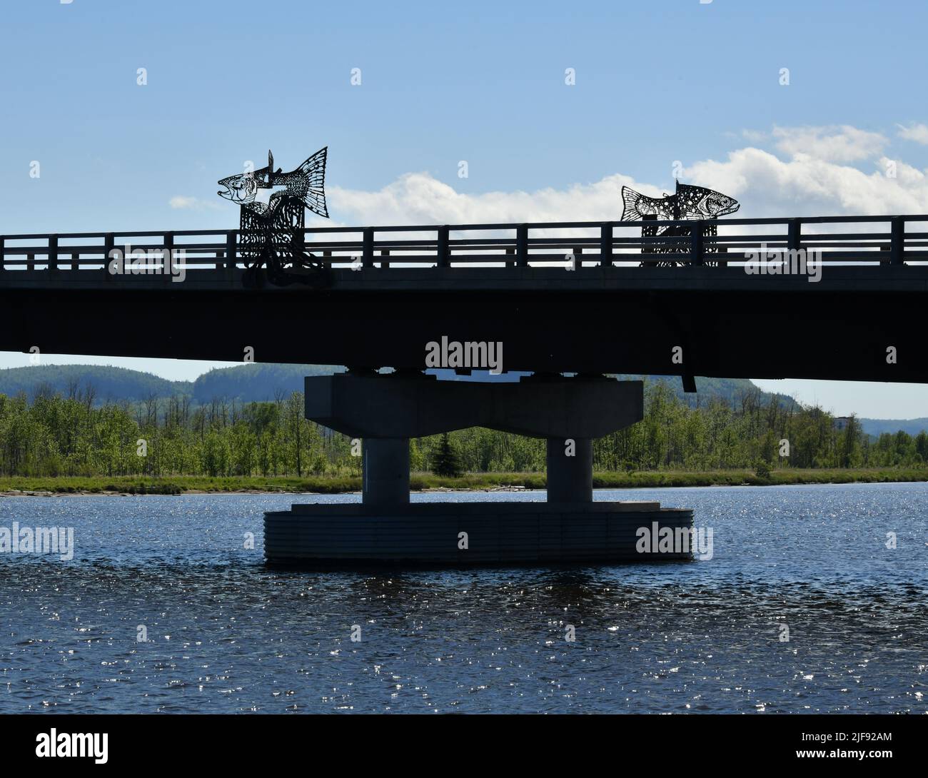 Un pont avec des œuvres d'art en fer traverse une rivière à Thunder Bay, Ontario, Canada, tandis que des collines vertes en arrière-plan. Banque D'Images