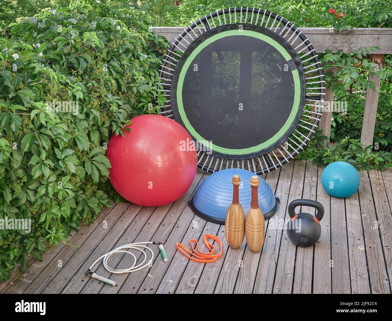 Home Gym concept - slam et balles suisses, bosu ball, fer kettlebell, mini trampoline, corde de saut lourd, Bande de résistance et clubs indiens en bois sur un Banque D'Images