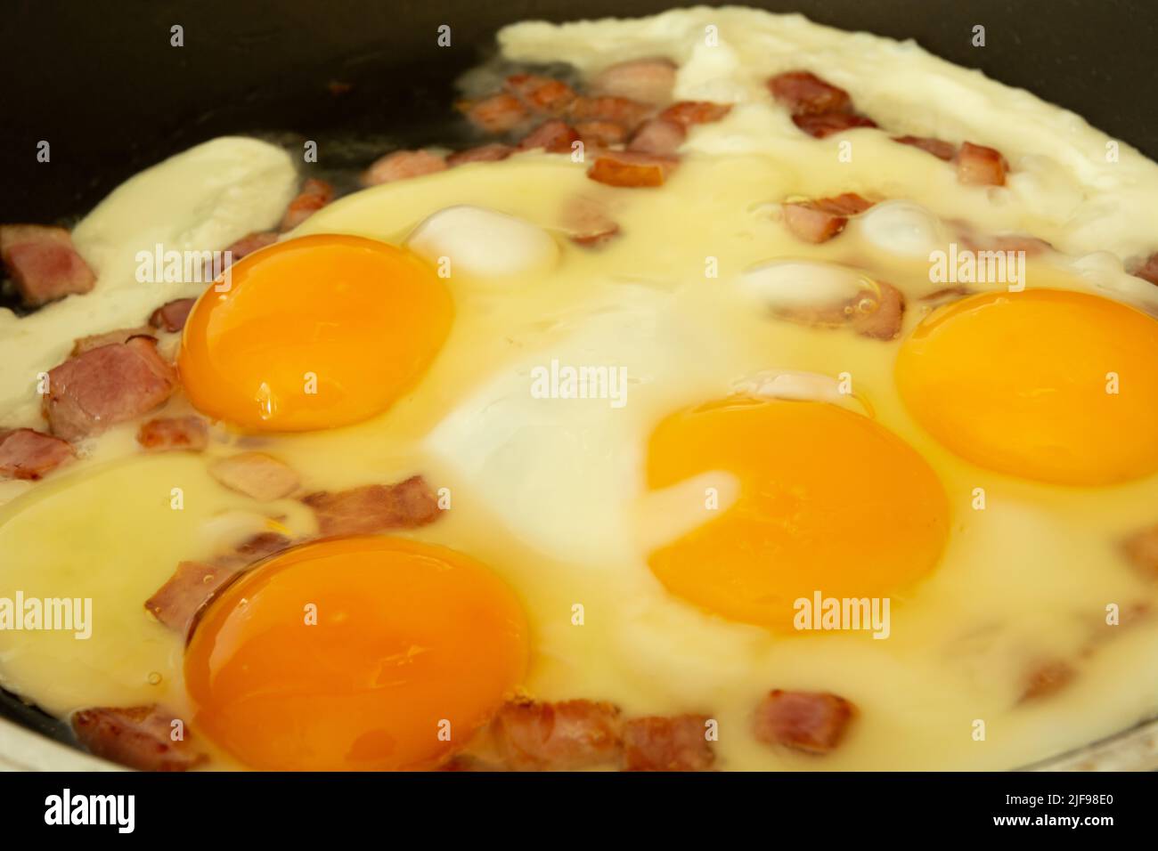 Faire frire des œufs brouillés avec du bacon dans une poêle Banque D'Images