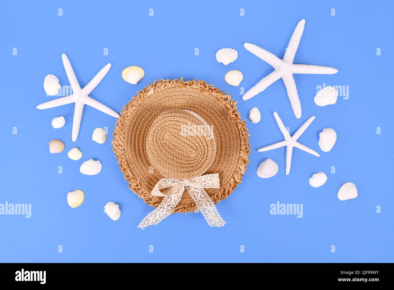 Étoile de mer blanche, coquillages et chapeau de paille d'été sur fond bleu Banque D'Images