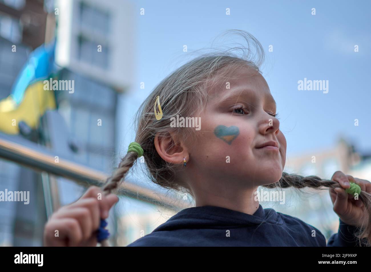 Fille avec drapeau d'Ukraine peint jaune et bleu. Arrêter la guerre et la puissance de l'Ukraine, le patriotisme. Les enfants soutiennent l'Ukraine. Pas de guerre. Priez pour l'Ukraine. Banque D'Images
