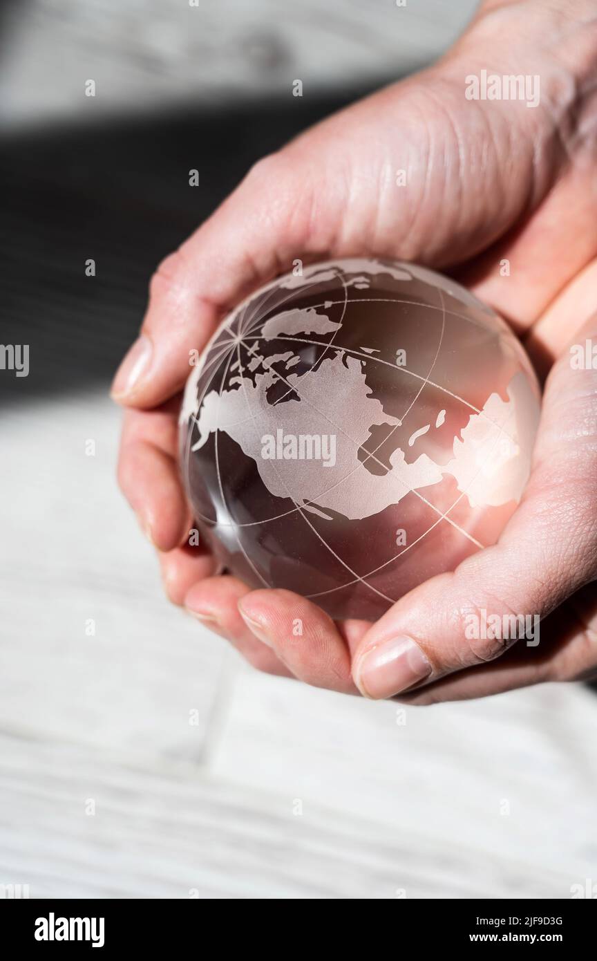 Gros plan des mains des femmes avec un globe en cristal sur un fond boisé. Banque D'Images