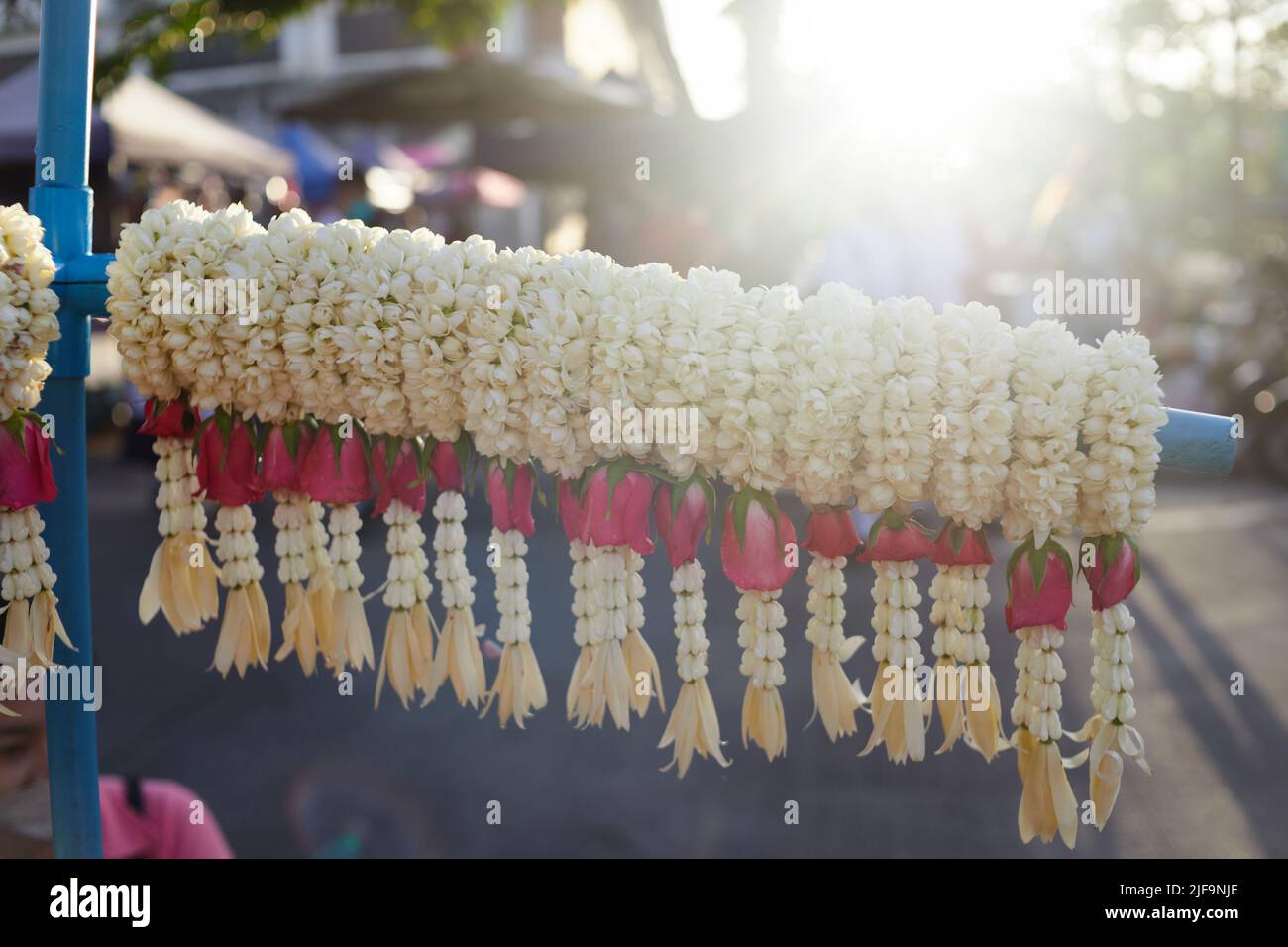 Jasmin frais mélangé à des guirlandes de roses rouges et de fleurs de couronne suspendues pour la vente au détail Banque D'Images