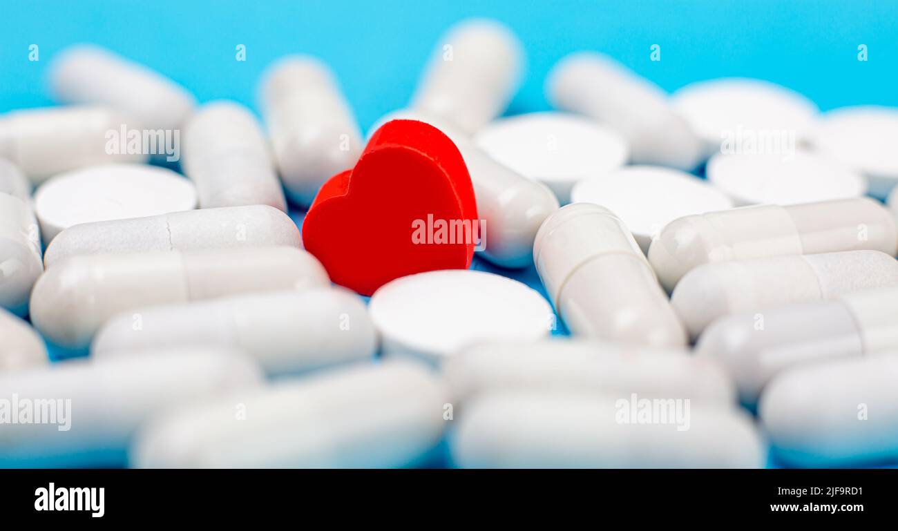 Pilule rouge en forme de coeur sur un fond de pilules blanches et un fond bleu. Le concept de l'addiction d'amour, drogues d'amour, Saint-Valentin et Banque D'Images