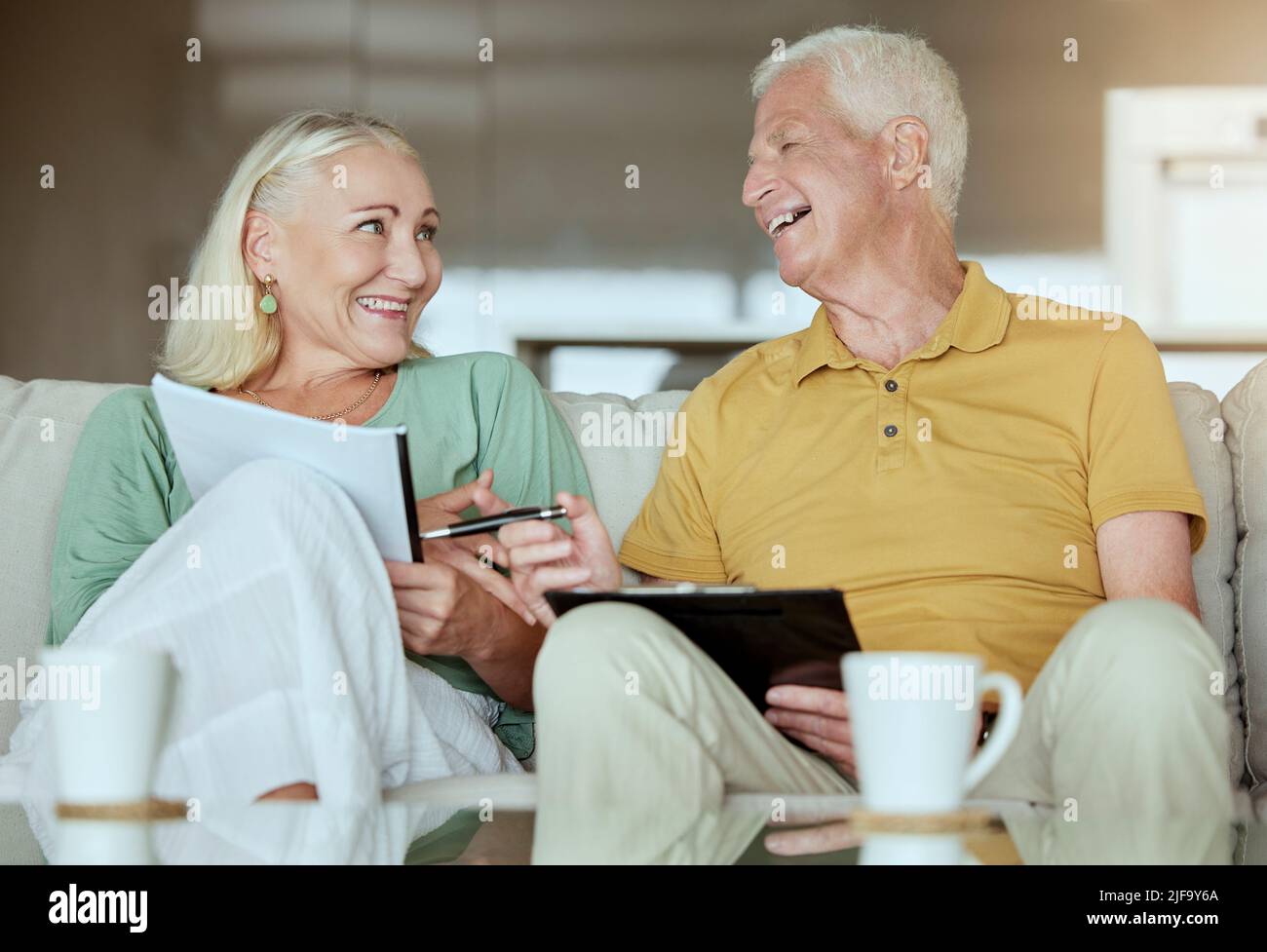 Un couple de personnes âgées heureux vérifie leur financement et planifie leur retraite. Homme et femme caucasiens âgés souriant tout en planifiant et en faisant de la paperasserie à la maison Banque D'Images