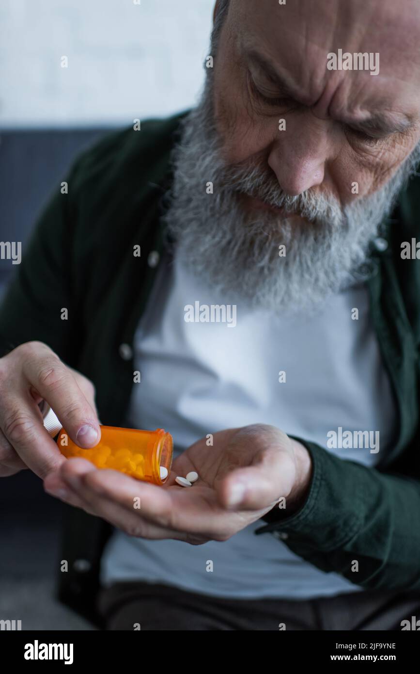 mécontent homme âgé avec un flacon de rétention de cheveux gris avec des pilules d'antidépresseurs Banque D'Images