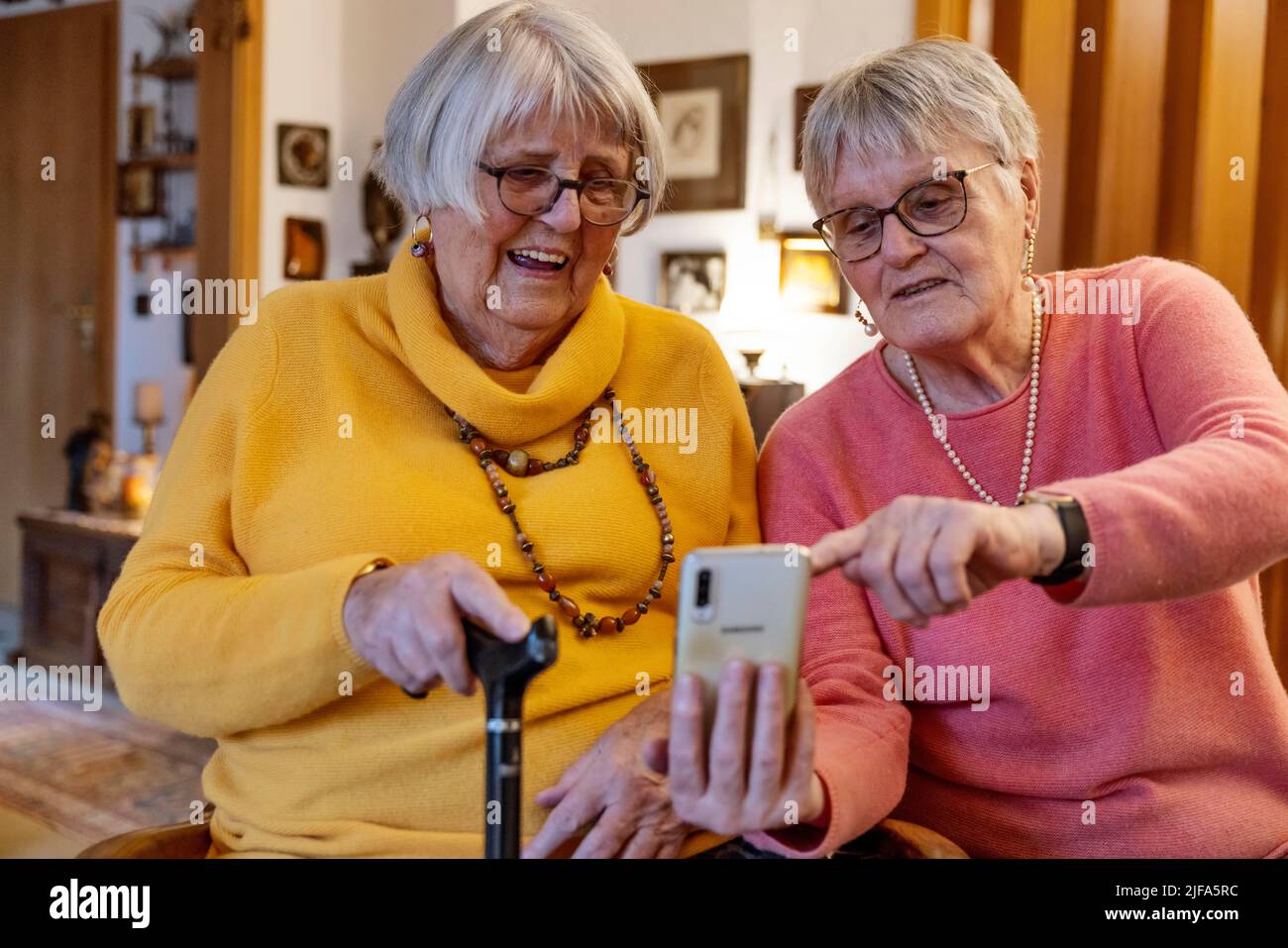 Deux personnes âgées, sœurs, regardant un smartphone à la maison, Bocholt, Rhénanie-du-Nord-Westphalie, Allemagne Banque D'Images