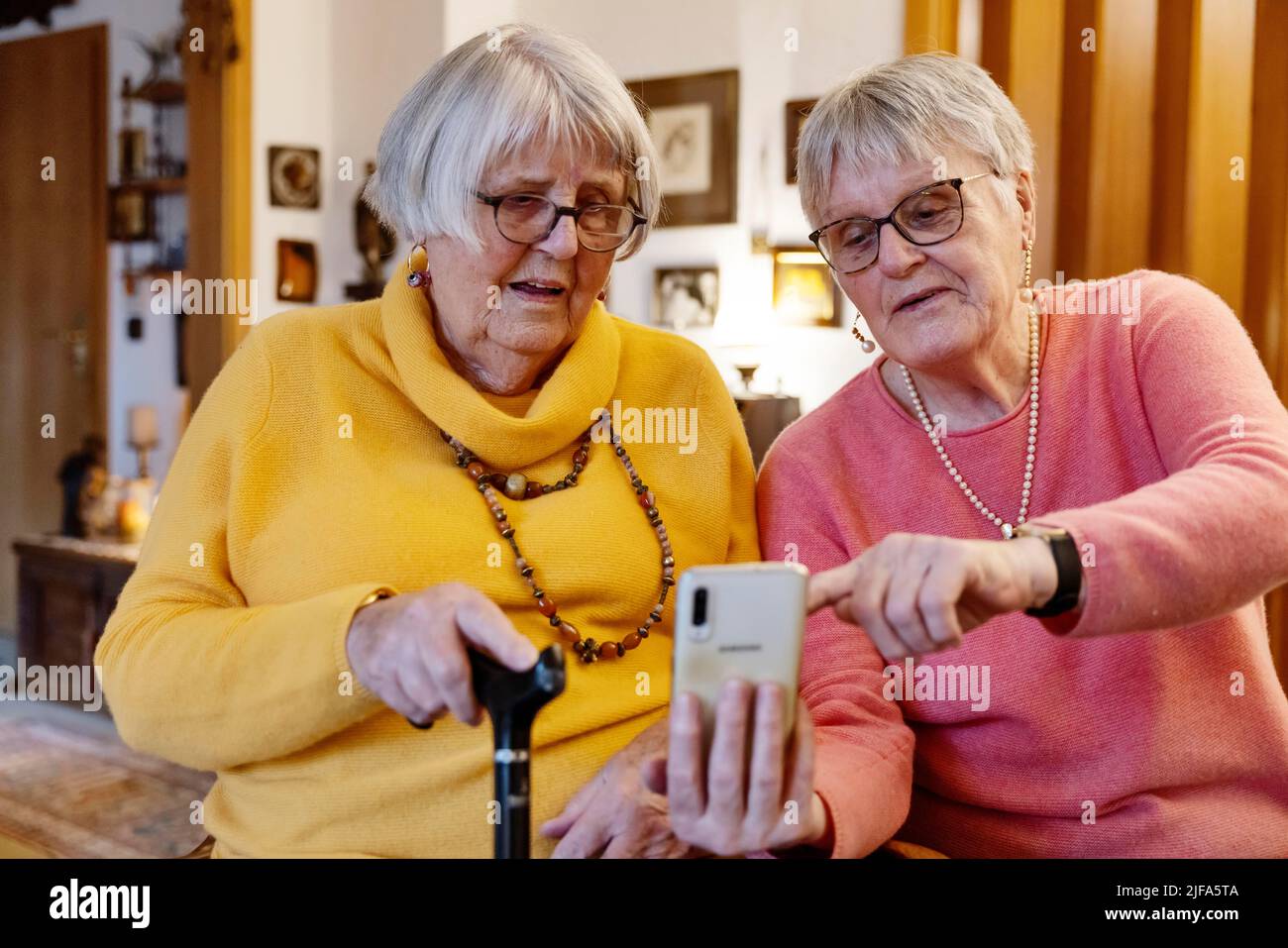 Deux personnes âgées, sœurs, regardant un smartphone à la maison, Bocholt, Rhénanie-du-Nord-Westphalie, Allemagne Banque D'Images