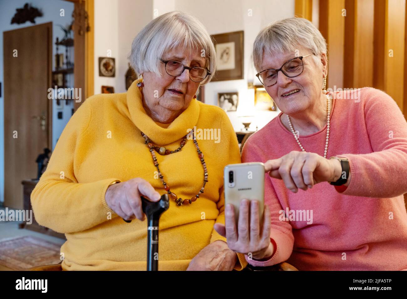 Deux personnes âgées, sœurs, regardant un smartphone à la maison, Bocholt, Rhénanie-du-Nord-Westphalie, Allemagne Banque D'Images