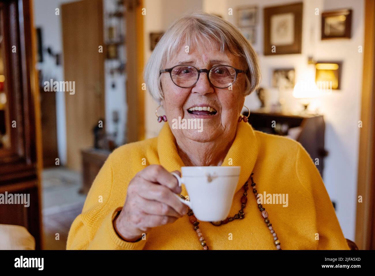 Femme âgée à la maison tenant une tasse de café avec un sourire, Bocholt, Rhénanie-du-Nord-Westphalie, Allemagne Banque D'Images