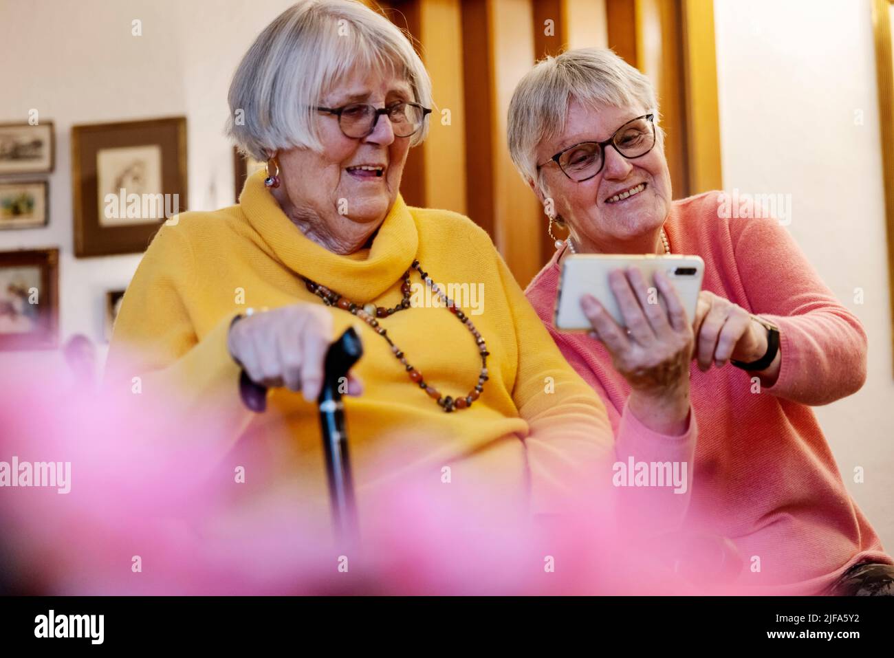 Deux personnes âgées, sœurs, regardant un smartphone à la maison, Bocholt, Rhénanie-du-Nord-Westphalie, Allemagne Banque D'Images