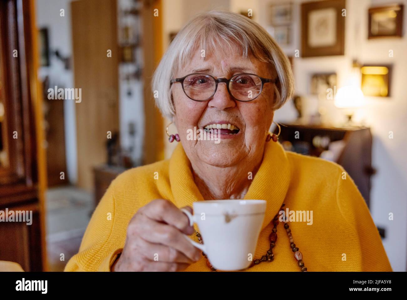 Femme âgée à la maison tenant une tasse de café avec un sourire, Bocholt, Rhénanie-du-Nord-Westphalie, Allemagne Banque D'Images