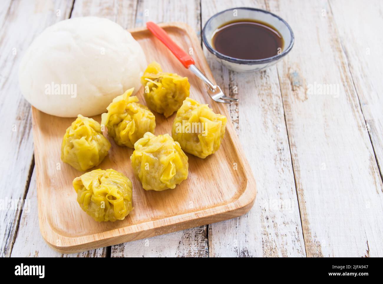 Petits pains chinois et boulettes en plaque de bois sur fond de bois Banque D'Images