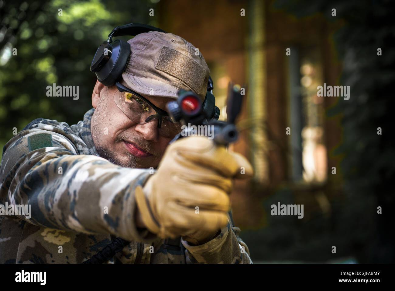 Jeune homme au cours de formation tactique de la police civile. Homme avec un fusil dans un casque militaire de protection auditive tactique uniforme. Formation de la police dans la galerie de tir avec arme. Mise au point sélective à portée de main. Banque D'Images