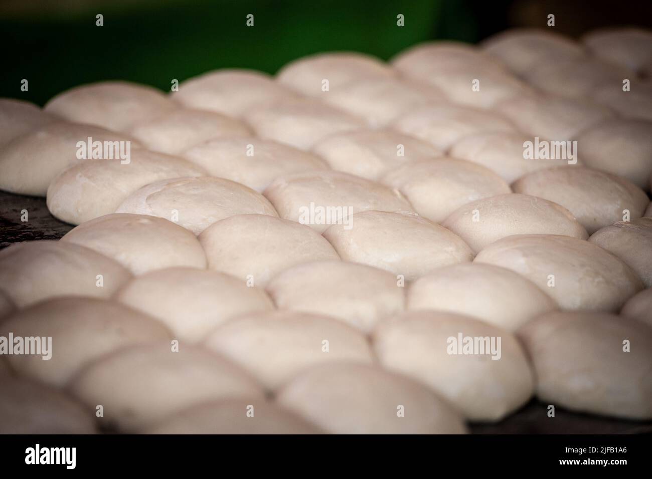 Image de pâte à pain crue, en forme de petits pains, en groupe, dans une boulangerie, étant prêt à se faire cuire au four. Banque D'Images