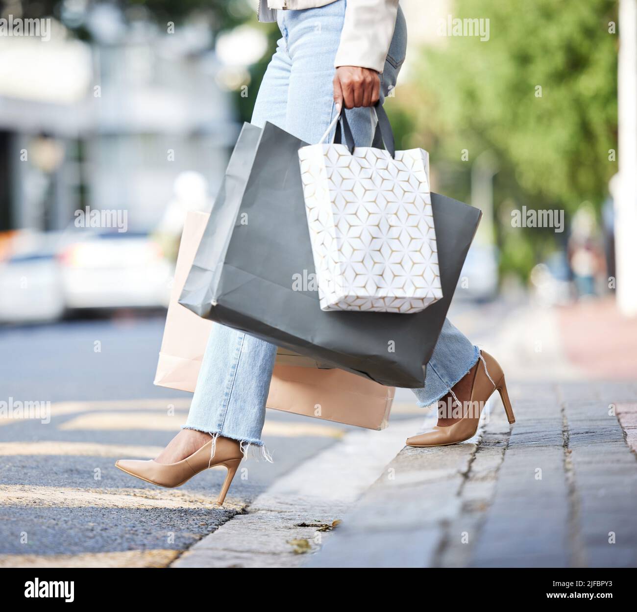 Femme afro-américaine à la mode inconnue marchant dans la rue dans la ville et portant des sacs de détail après le shopping. Femme noire haute mode Banque D'Images