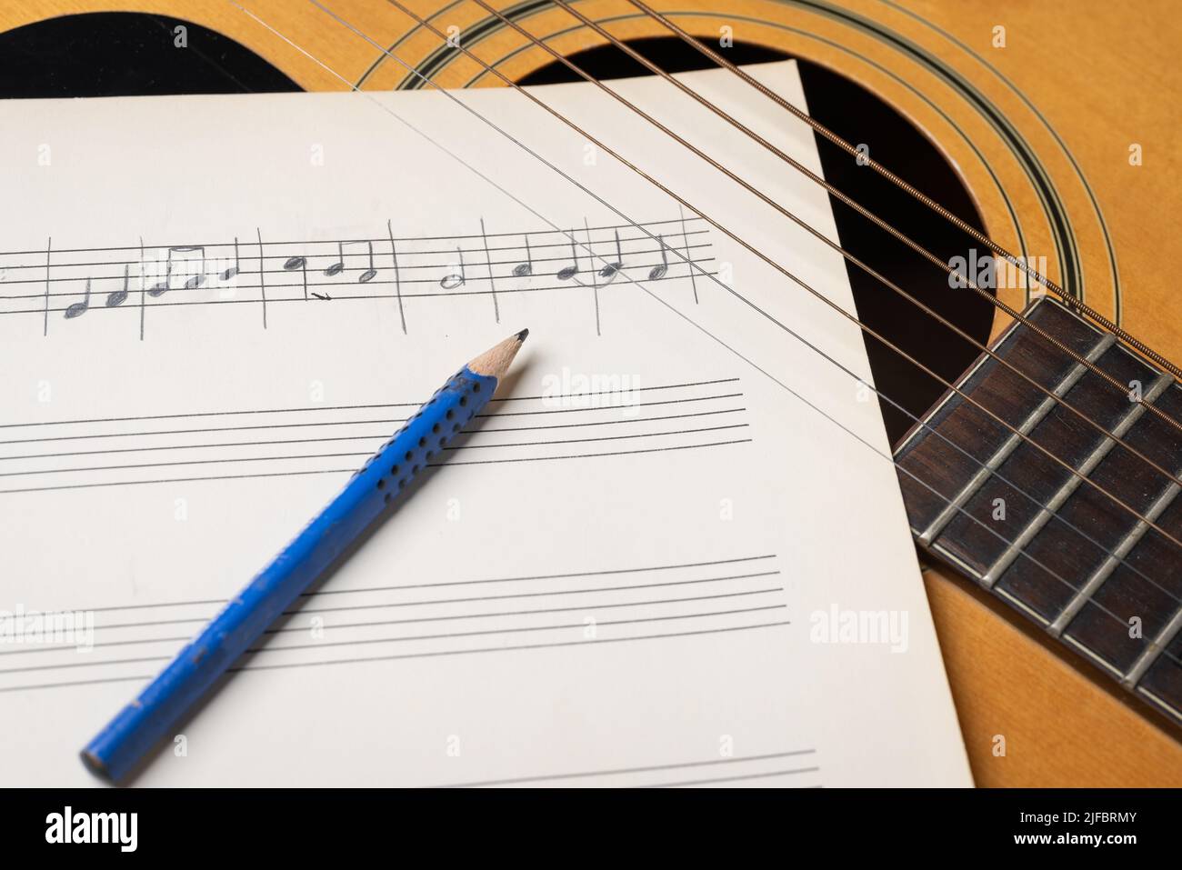 Scène d'enregistrement de musique avec guitare, feuille de musique et crayon sur table en bois Banque D'Images