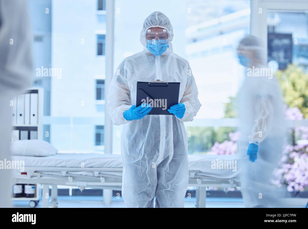Biologiste lisant un rapport médical à l'hôpital. Biochimiste lisant les documents sur la planchette à pince dans la chambre d'hôpital de quarantaine. Spécialiste médical en Banque D'Images