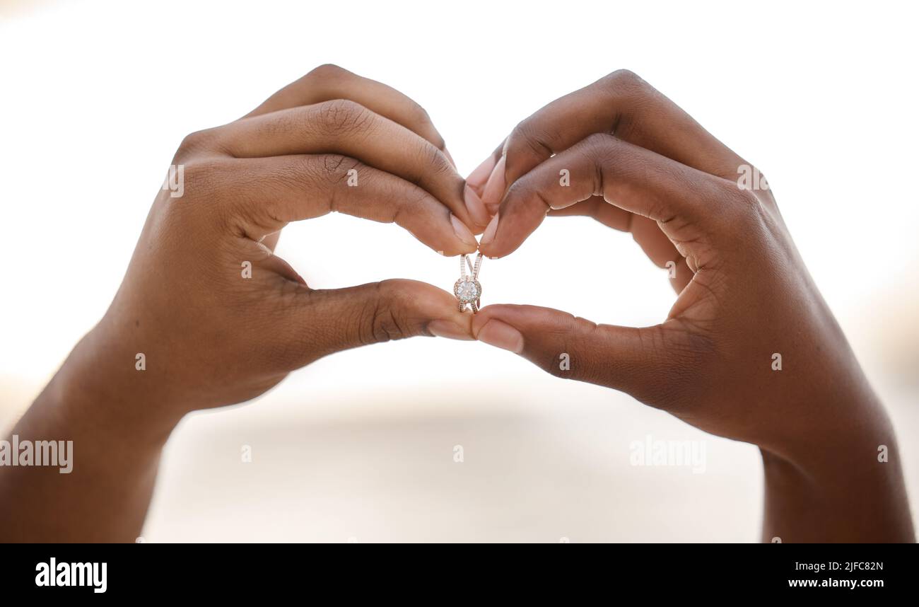 Gros plan des mains sur un homme afro-américain en forme de coeur tout en tenant un anneau. Homme faisant un geste de coeur avec ses mains tout en montrant un Banque D'Images