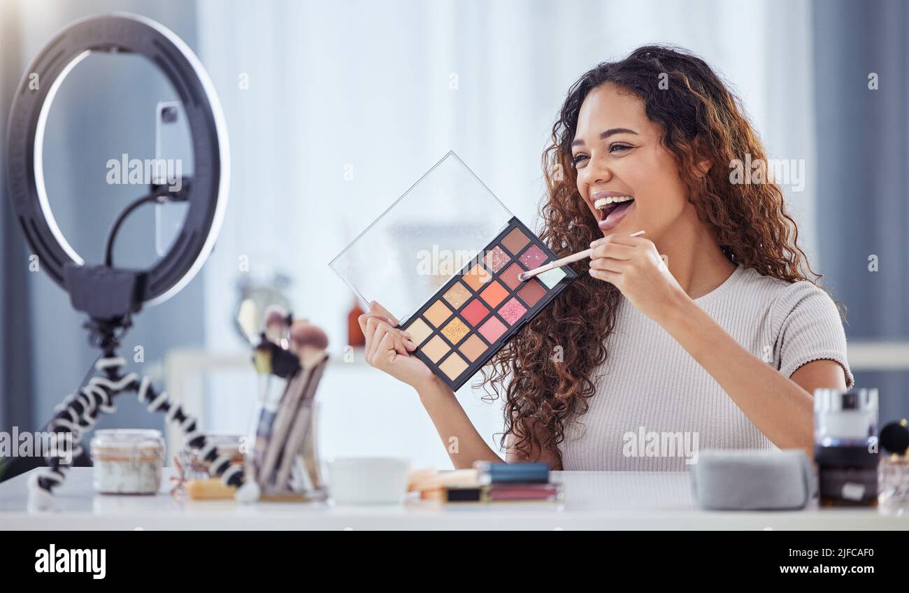 Une femme hispanique enregistrant un tutoriel de maquillage pour son blog de beauté avec son téléphone tout en étant assis à la maison. Influenceur afro-américain vit Banque D'Images