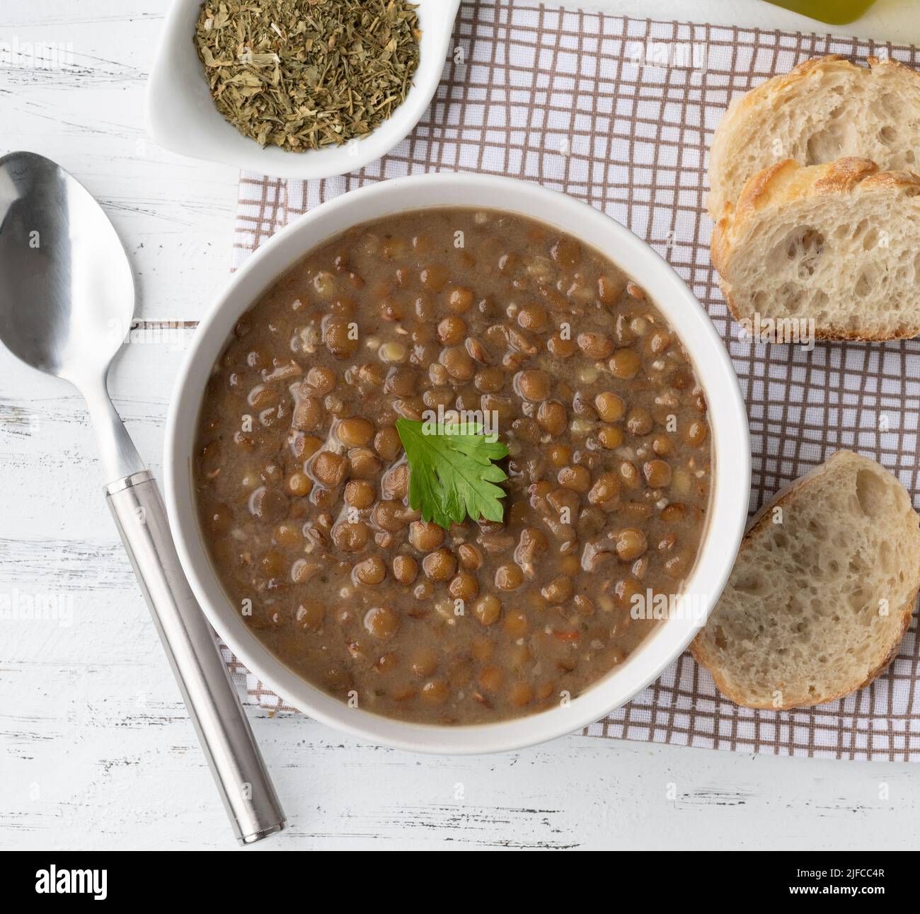 Faire revenir la soupe de lentilles dans un bol avec des tranches de pain et assaisonner sur une table en bois. Banque D'Images