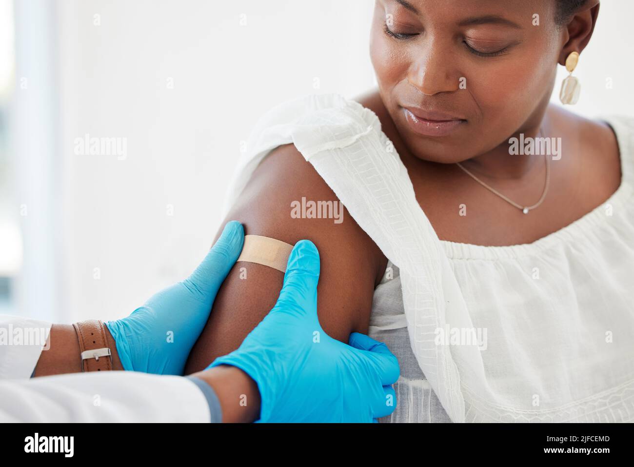 Femme afro-américaine regardant son médecin appliquer un plâtre main d'un médecin appliquant un plâtre au bras d'un patient. Patient et médecin dans un Banque D'Images