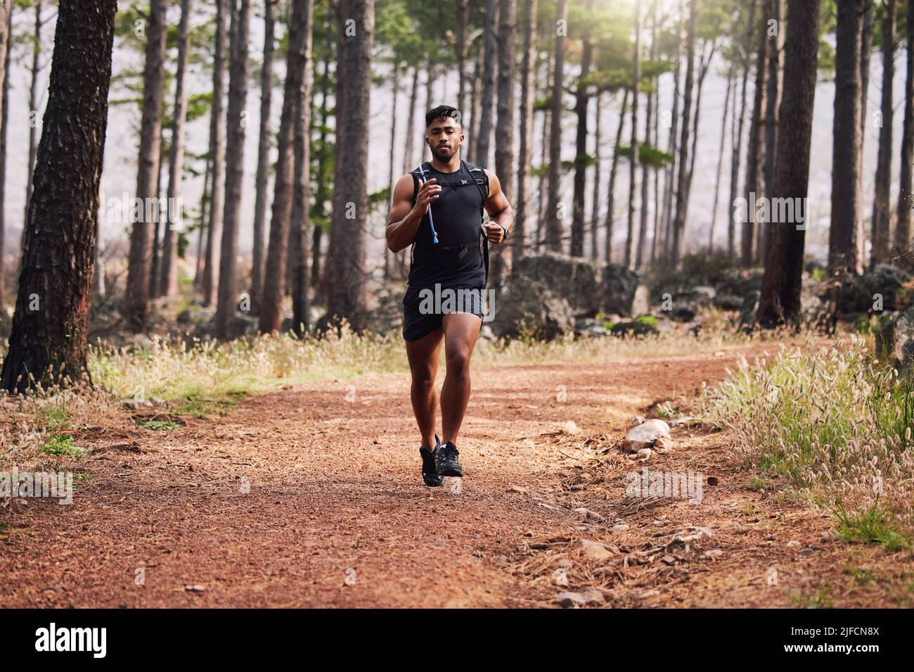 Jeune course mixte de forme d'athlète masculin courir dans une forêt à l'extérieur dans la nature. L'exercice est bon pour la santé et le bien-être. Jogging dans un parc seul pendant le Banque D'Images