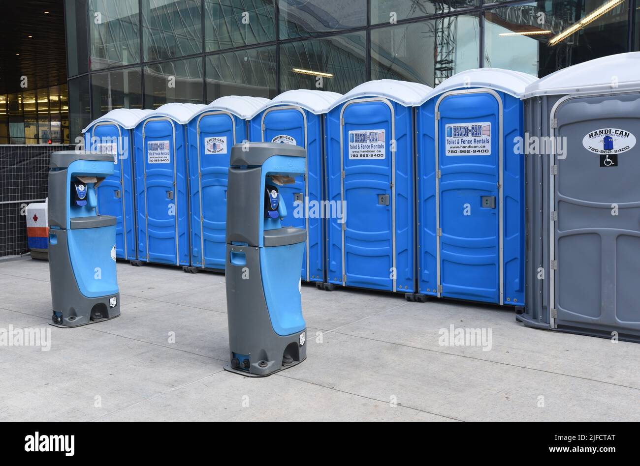 Toilettes portatives et stations de lavage (en premier plan) à l'extérieur de l'aréna Rogers, à Edmonton. Alberta, Canada Banque D'Images