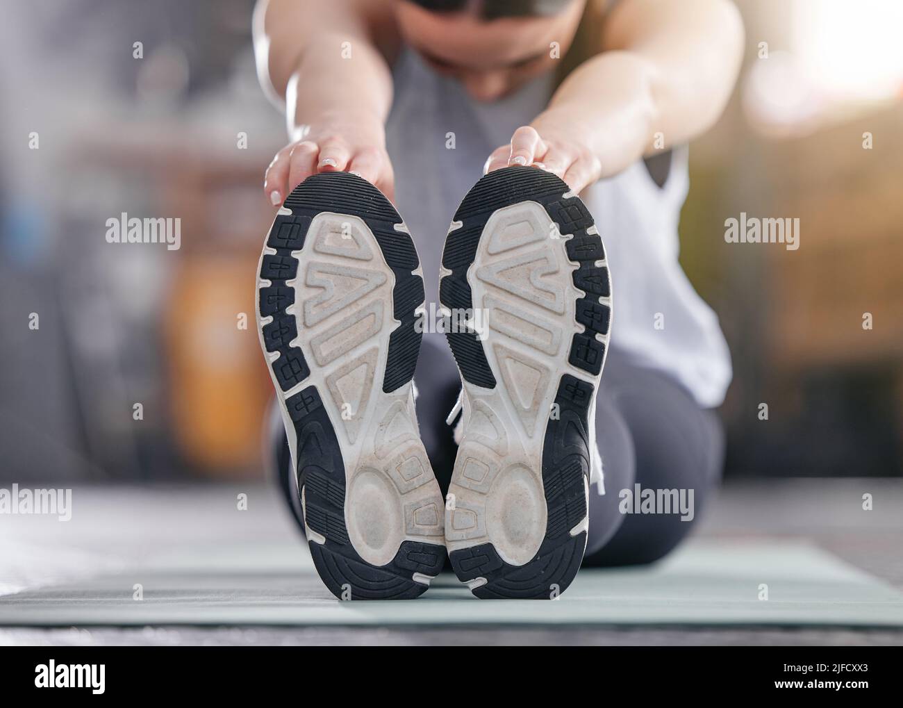 Gros plan d'une femme caucasienne active touchant ses pieds et étirant ses jambes pour se réchauffer afin d'éviter les blessures lors d'un exercice en salle de sport. Semelle inférieure de Banque D'Images