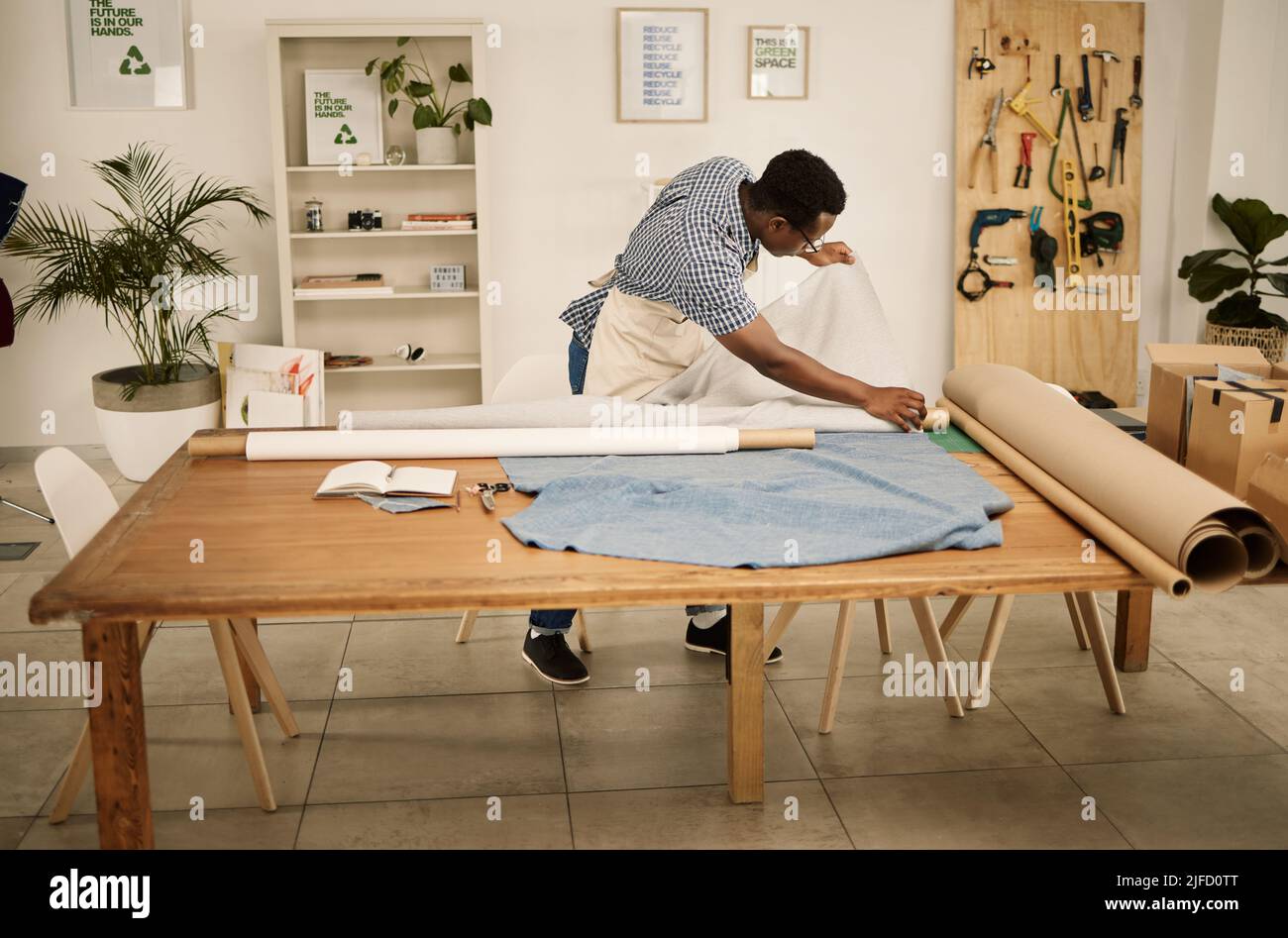 Un concepteur afro-américain qui cherche du tissu. Rouleau de vérification de matériau pour jeune designer de mode. Couturière vérifiant ses textiles. Entrepreneur créatif Banque D'Images