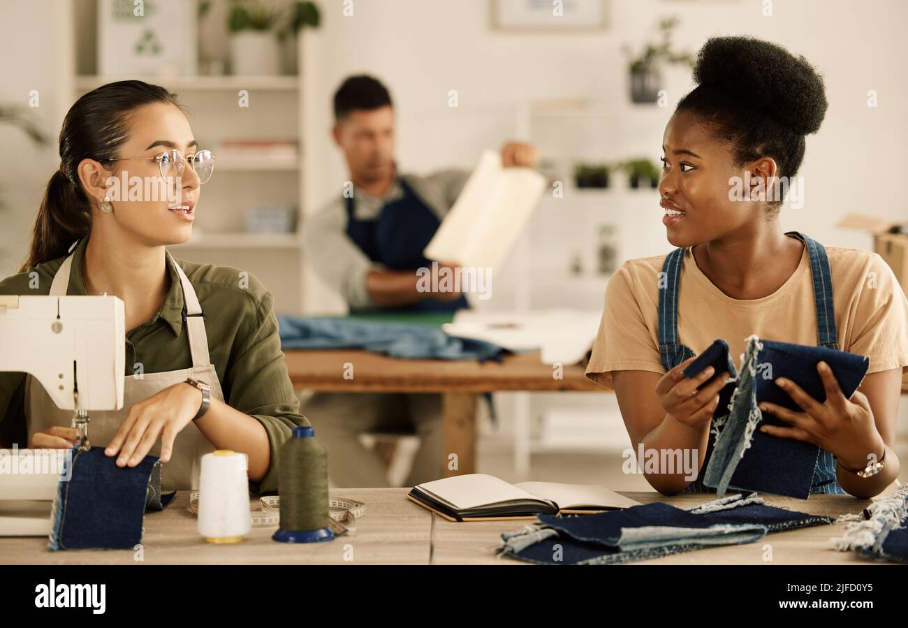 Deux créateurs de mode collaborant. Diverses femmes d'affaires se mêle dans un studio. Les collègues de couturière parlent du denim. Deux Banque D'Images