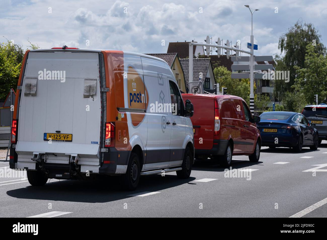 Le minibus de livraison de la société postale néerlandaise 'PostNL' attend devant un feu de circulation derrière d'autres voitures. Les feux stop sont visibles. Société de messagerie Banque D'Images