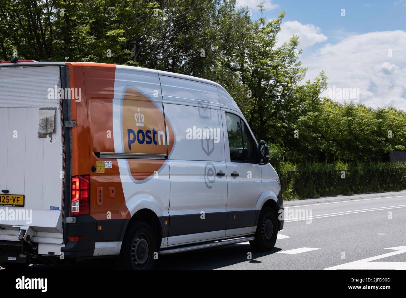 Le camion de livraison de la société postale néerlandaise « PostNL » conduit sur une route asphaltée pour livrer un colis au client suivant. Société de messagerie Banque D'Images