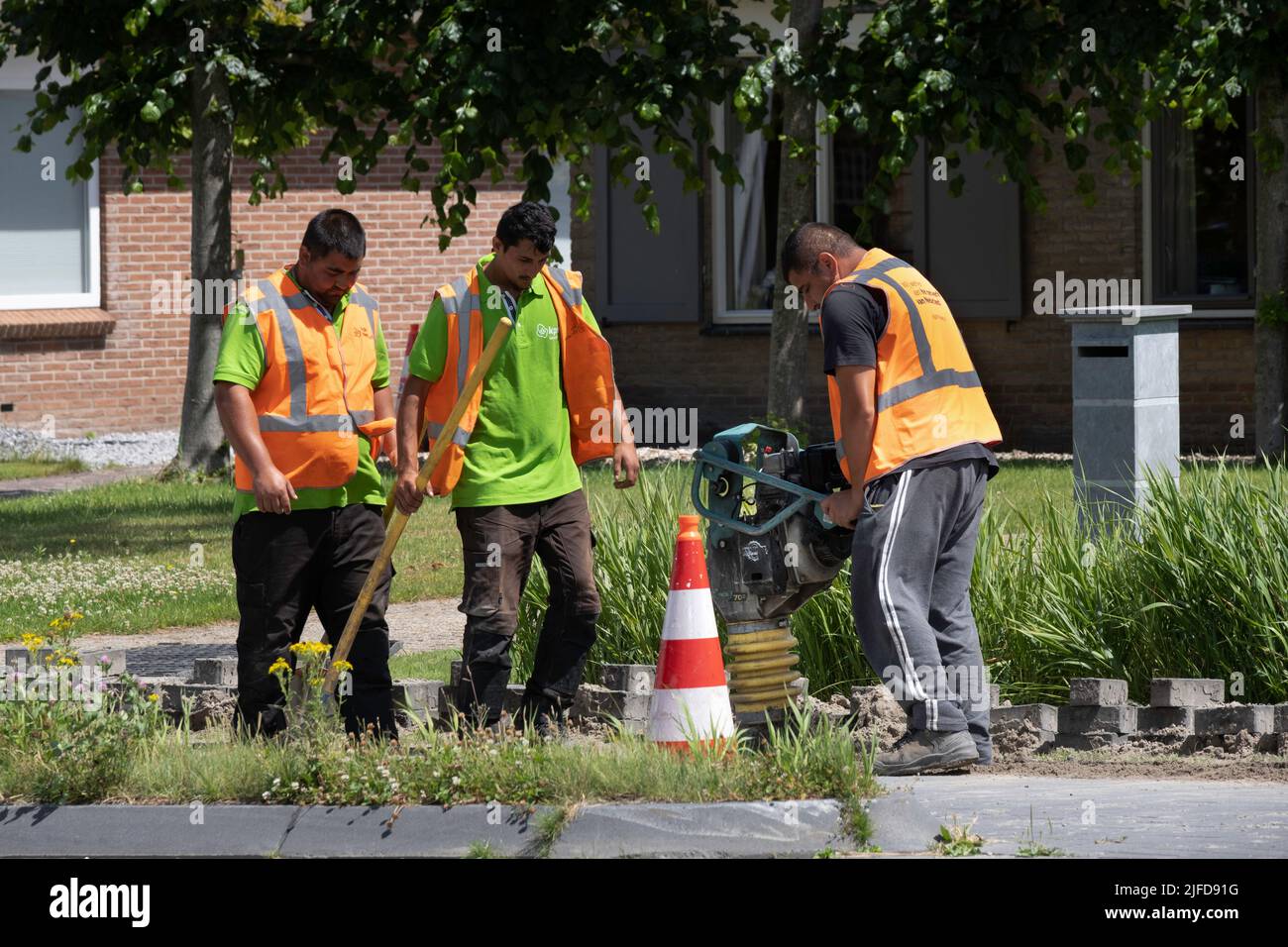 Employés de la compagnie de téléphone néerlandaise KPN travaillant avec une résistance aux vibrations portable pour tasser le sable après avoir posé des câbles. Travaux de rue Banque D'Images