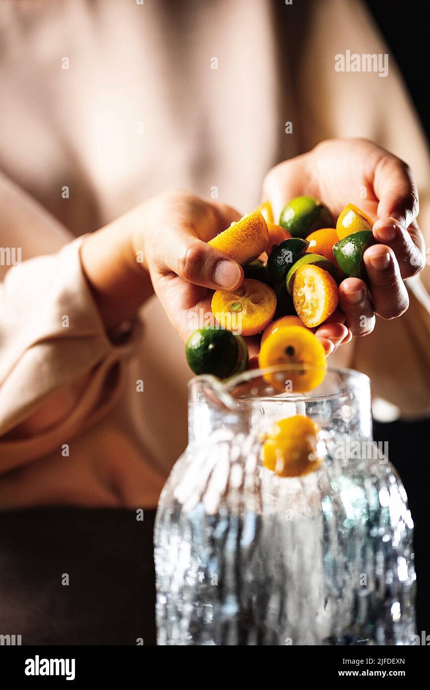 Remplissage du pot de boisson avec des kumquats et de petites limes, frais et fruité de boisson froide processus de fabrication - photo de stock Banque D'Images