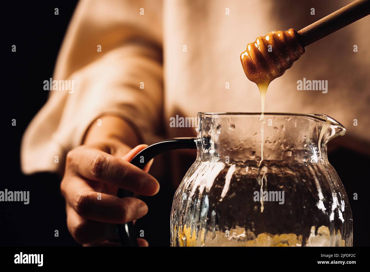 Ajouter du miel aux agrumes réfrigérés dans des bocaux en verre, frais et fruité boisson froide processus de fabrication - photo de stock Banque D'Images